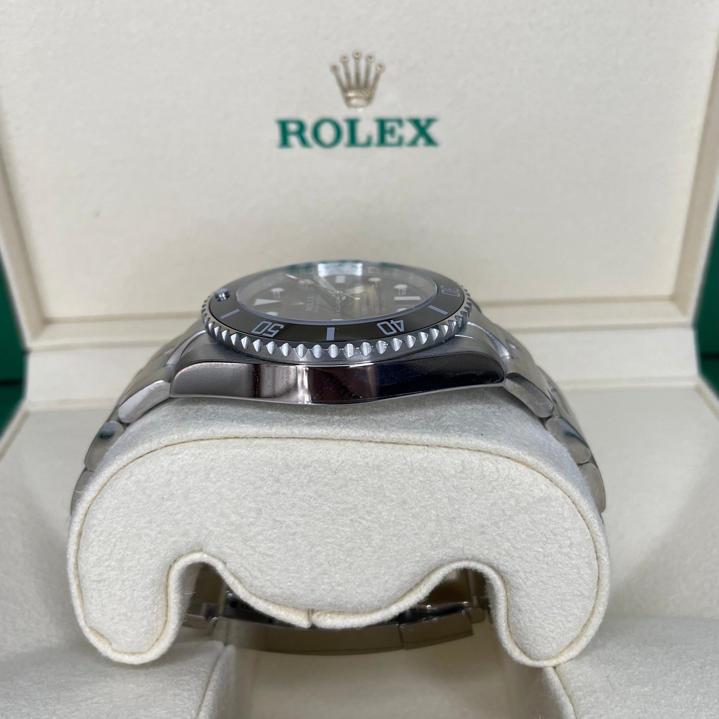 Orologio Rolex Replica Submariner con quadrante nero e cinturino in acciaio inox, esposto in una scatola con il logo rolex 