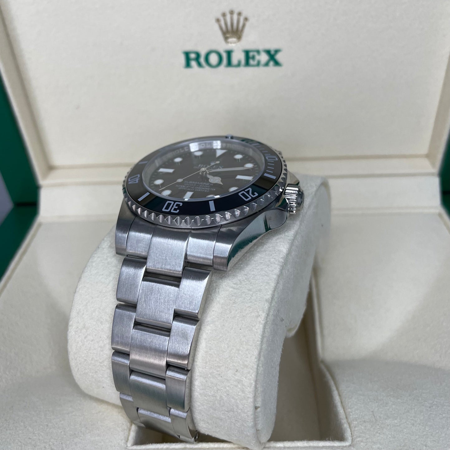 Orologio Rolex Replica Submariner con quadrante nero e cinturino in acciaio inox, esposto in una scatola con il logo rolex 