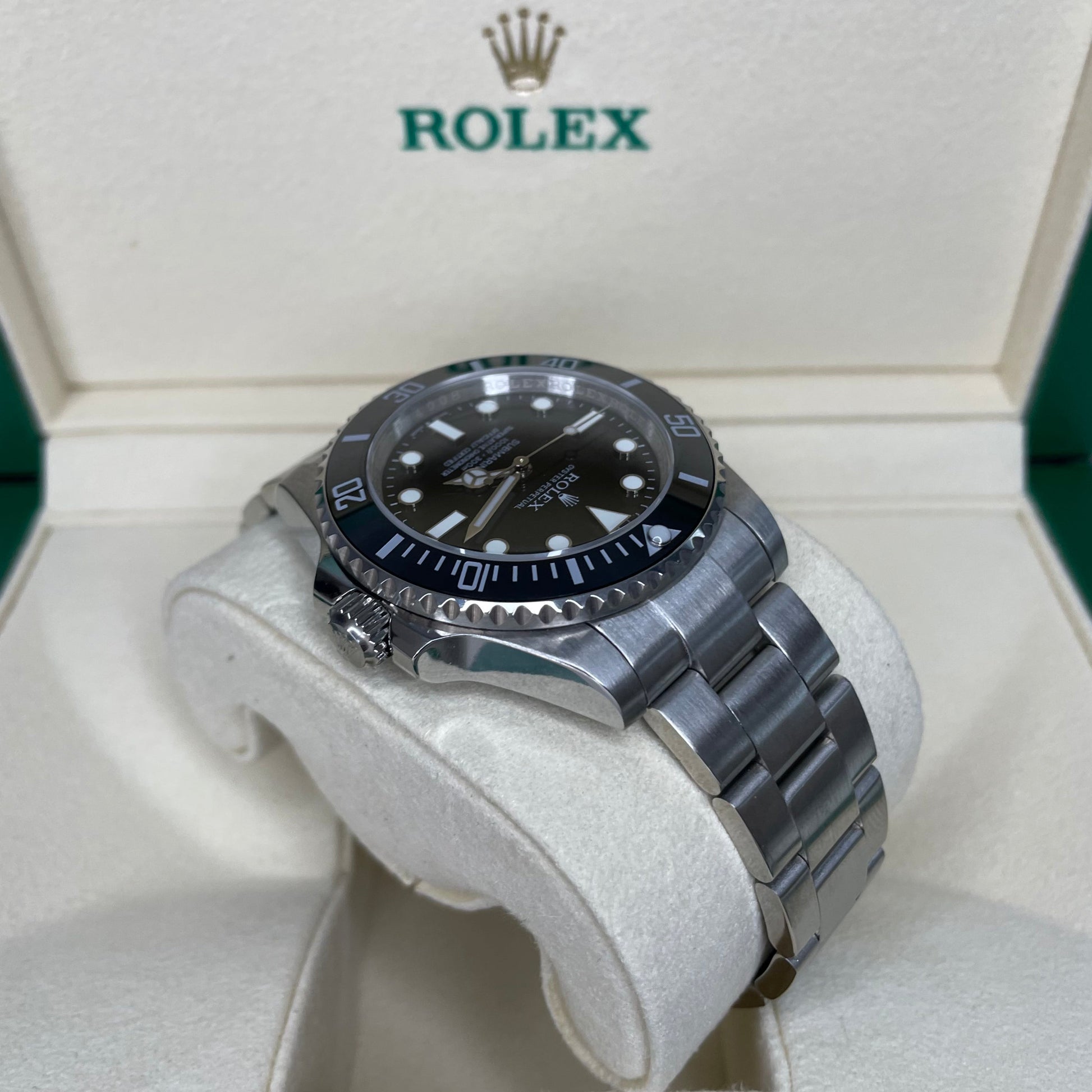 Orologio Rolex Replica Submariner con quadrante nero e cinturino in acciaio inox, esposto in una scatola con il logo rolex 